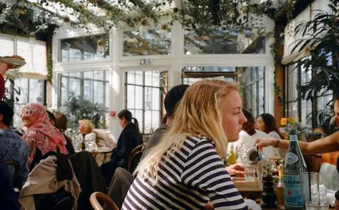 Busy Paris café terrace with people dining under hanging plants
