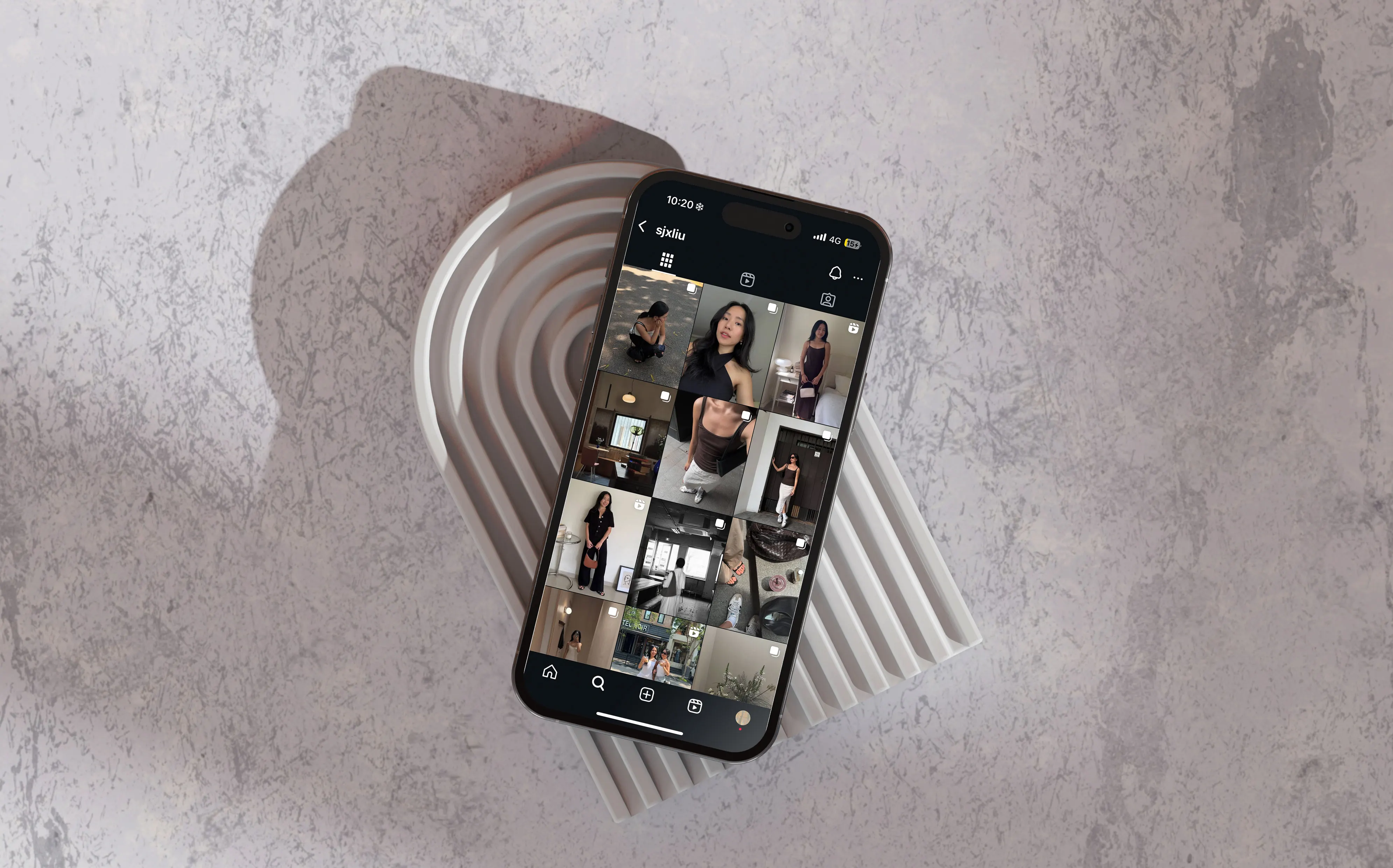 Phone showing a grid of social posts, resting on a ridged stone tray