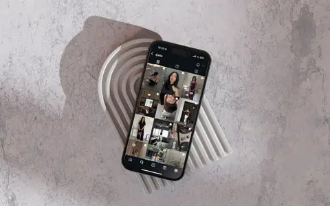 Phone showing a grid of social posts, resting on a ridged stone tray
