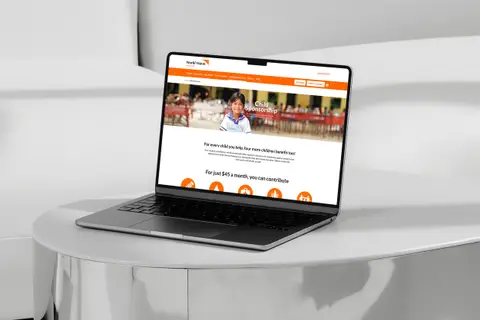 Laptop on a white side table showing the redesigned World Vision sponsorship page